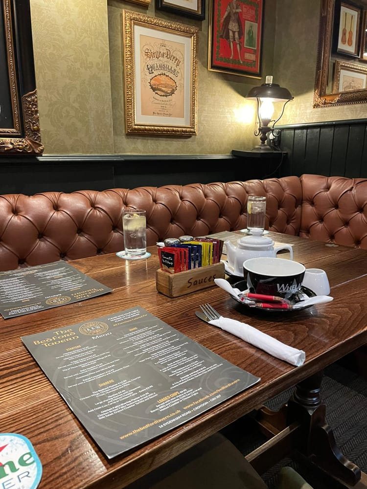A menu laid on a wooden table in one of the leather booths, with the sauces and cutlery ready