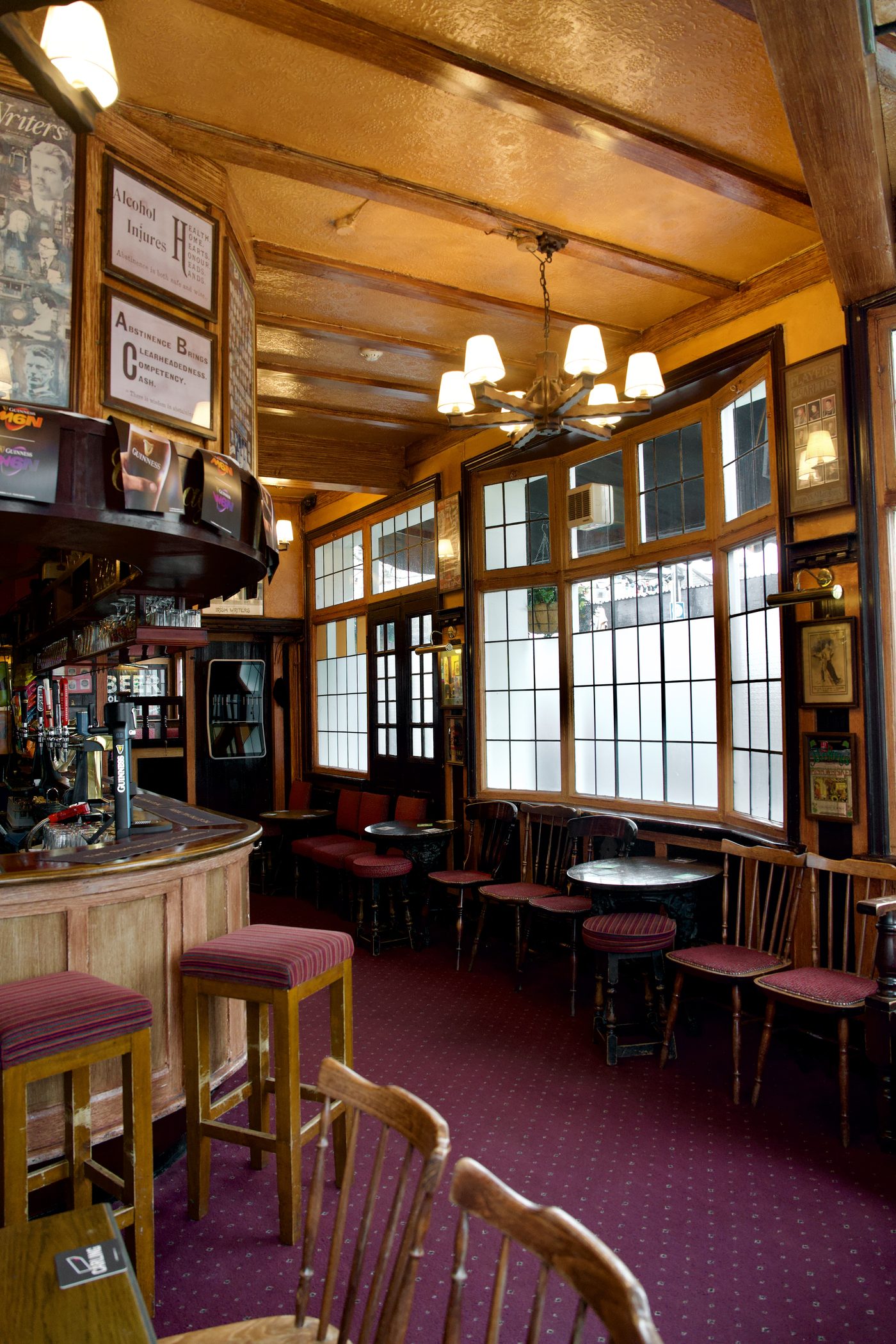 A room off the bar: a beamed ceiling and chandelier, a bay window of leaded glass, red carpet and framed Victorian temperance notices
