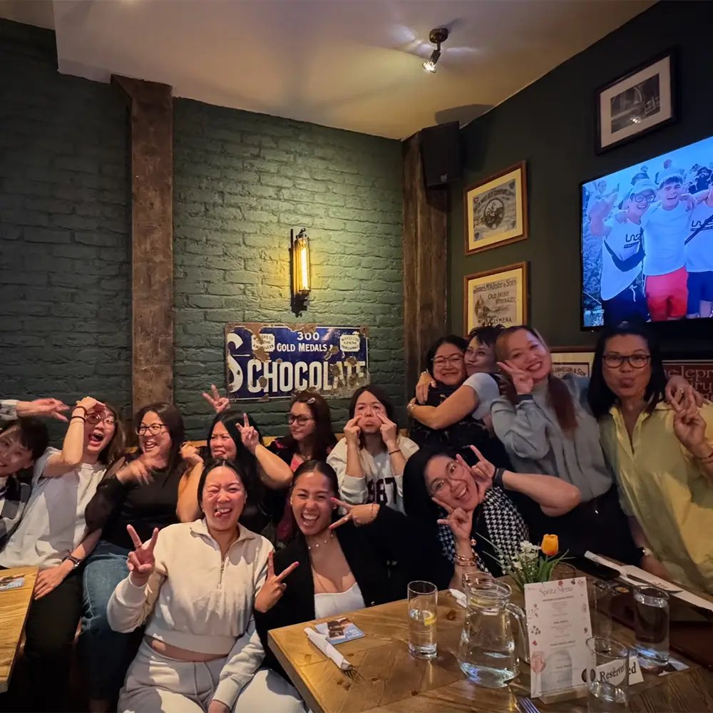 A group celebrating around a table, a vintage Chocolate advertising sign on the wall behind