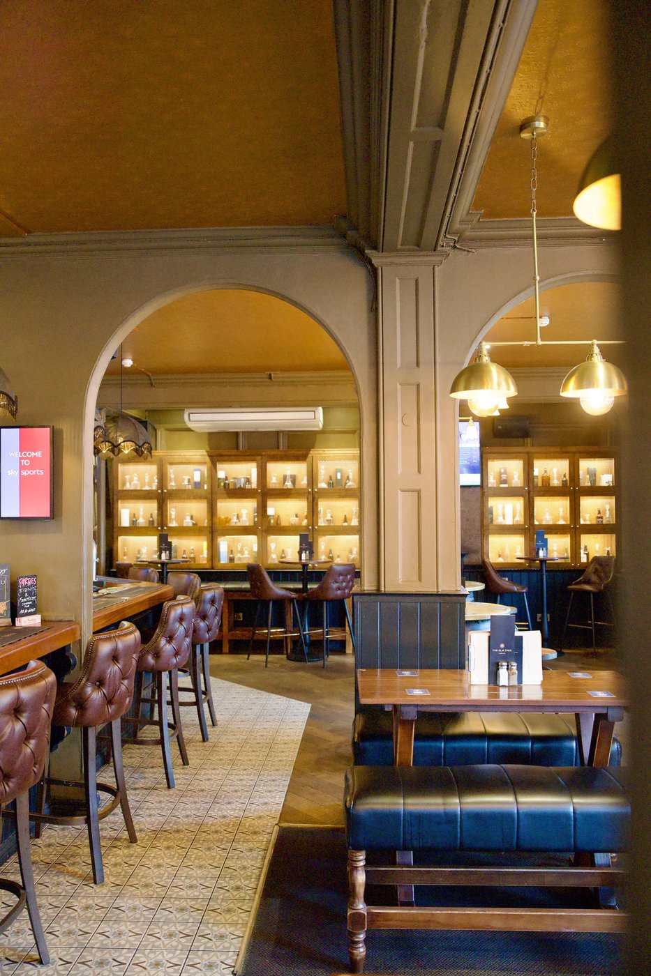 An arched dining room with blue banquettes, framed pictures and pendant lighting