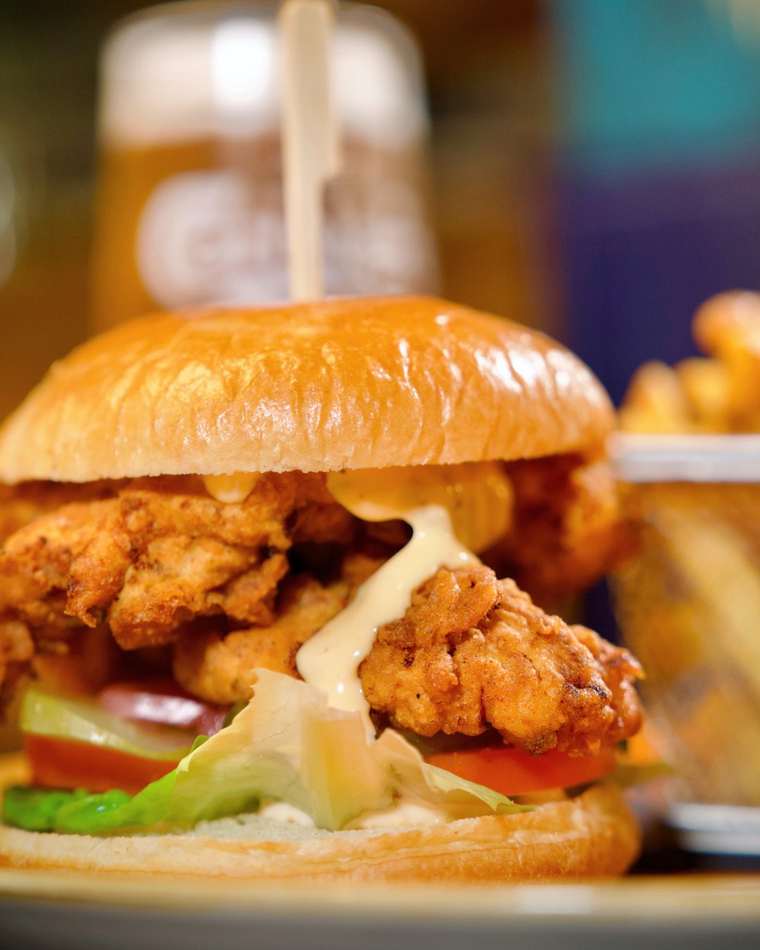 A fried chicken burger in a brioche bun with lettuce and tomato